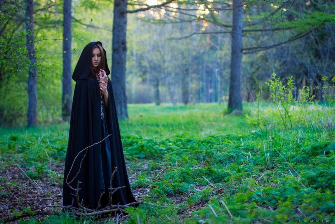 Женщина в черном плаще с капюшоном